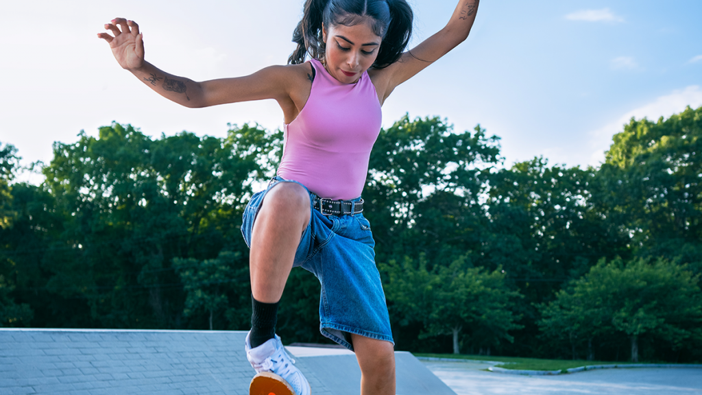 An action shot of Lizzie performing a trick on her skateboard.